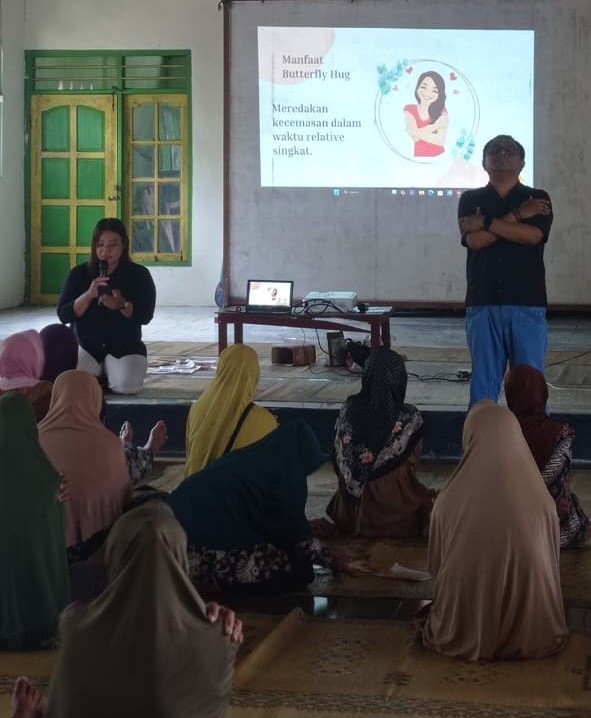 Lansia sedang mempraktikkan teknik Butterfly Hug, yang membantu mengelola kecemasan dan menciptakan rasa tenang.