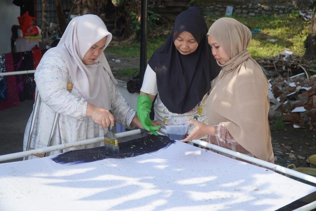 Sambil mengoleskan cat pada kain batik, anggota HWDI Kota Makassar memastikan cat meresap sempurna pada kain batik karya mereka